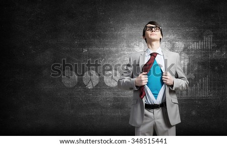 Young businessman acting like super hero and tearing his shirt off