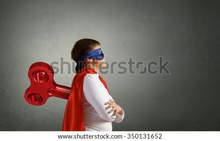 Little super active boy with key on back wearing super hero costume