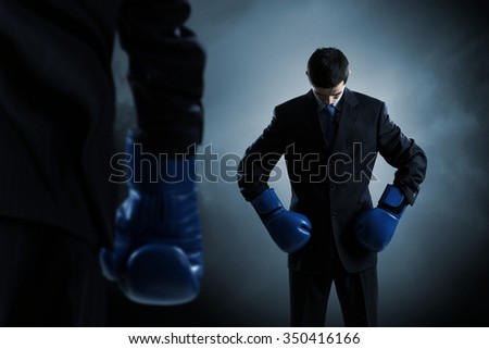 Determined businessman in suit and boxing gloves