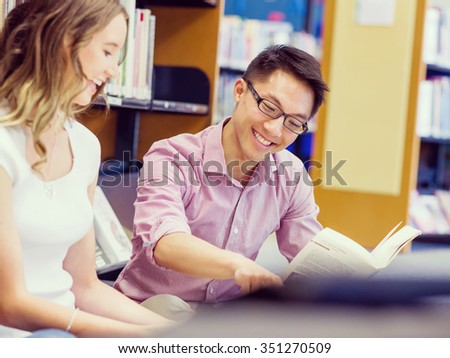 Two young students working together at the library