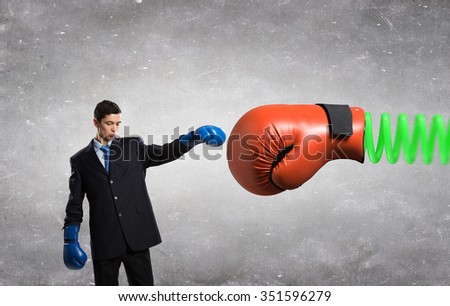 Determined businessman in boxing gloves fighting with glove on spring