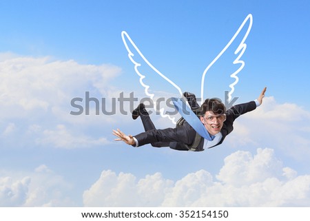 Young businessman with drawn wings flying in sky