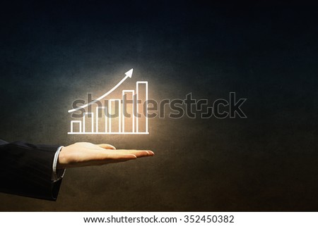 Hand of businessman on dark background showing glowing business growth concept
