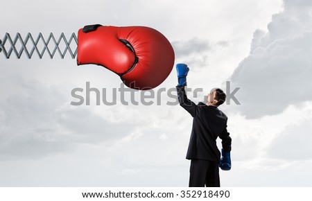 Determined businessman in boxing gloves fighting with glove on spring