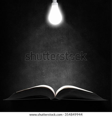 Opened book and glowing light bulb above pages