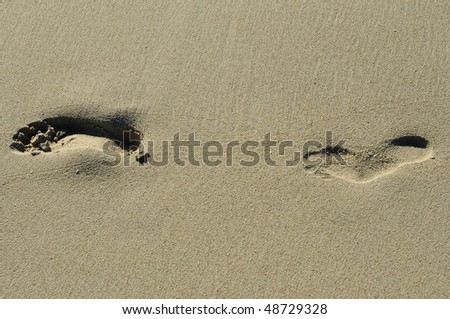 imprint of human feet in the sand on the beach