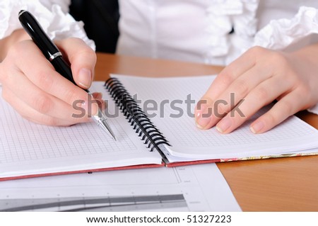 The hand of a young girl holding a black pen. Workplace business woman.