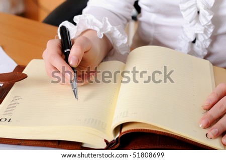 The hand of a young girl holding a black pen. Workplace business woman.