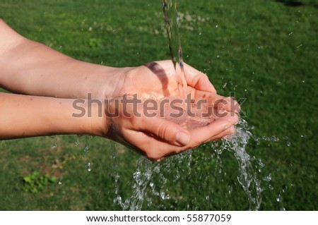 The hands of a young girl and a jet of water