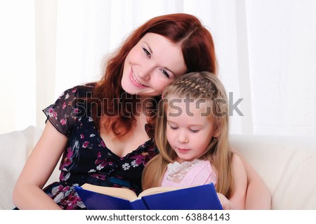The little girl and her mother read a book together on the couch