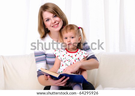 Mother and daughter reading a book together on the couch