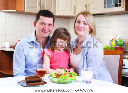 Dad, Mom and their little daughter lunching together in his kitchen.