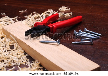 Shavings of wood, brick red and pliers on a dark background