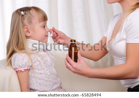 Little girl drinking cough syrup with a small spoon from the hands of moms