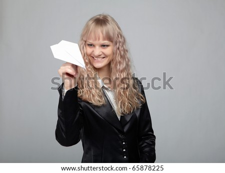 Funny business woman in a black suit with a gray background runs out of paper airplanes
