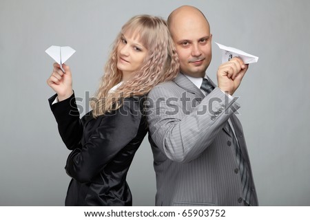 Funny business woman in a black suit and a bald businessman with a gray background run Aircraft