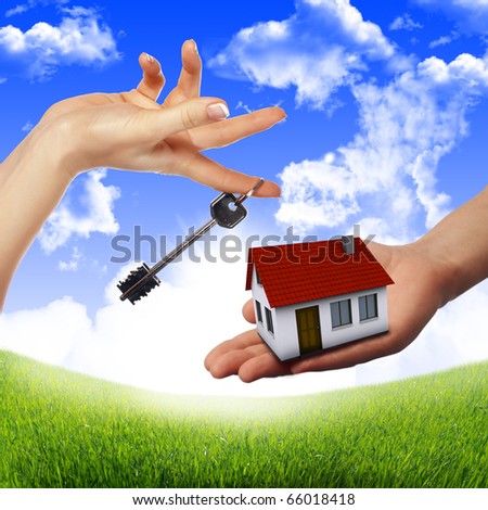 The House in the hands against the blue sky as a symbol of the real estate business.