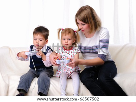 Little brother and sister and his mother played video games while sitting on the couch