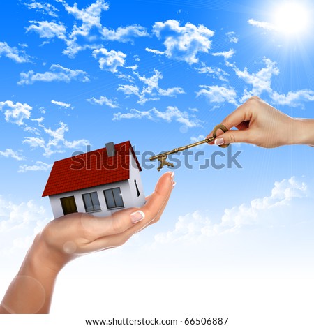 The House in the hands against the blue sky as a symbol of the real estate business.