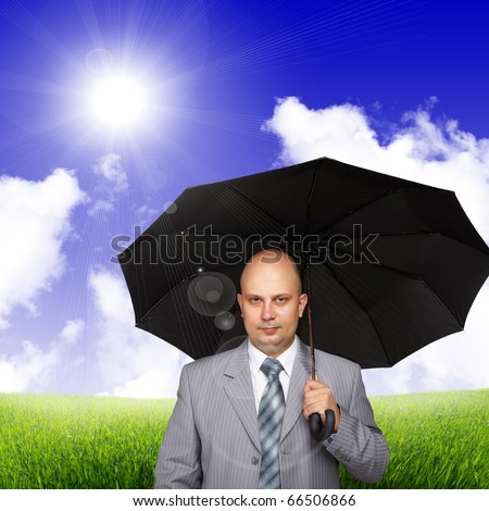Young successful business man with a black umbrella against the sky