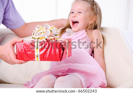 The father gives his young daughter in a red gift box with a white ribbon.