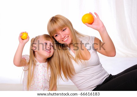Young mother and child spend time together. kept in the hands of oranges