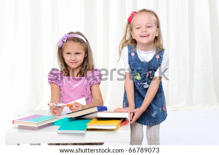 Little girls are studying literature. Reads a book while sitting at a white table.