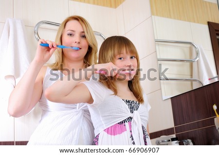A young girl and her mother woke up early in the morning brushing his teeth in his bathroom