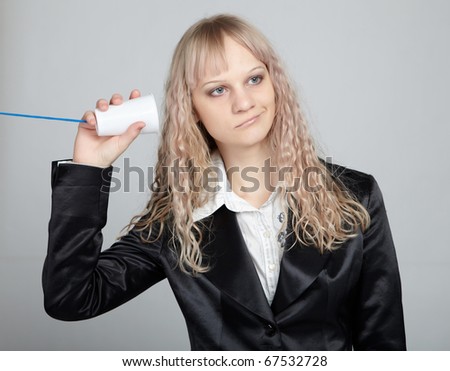 Funny business woman in a black suit with a gray background with a phone from a cup