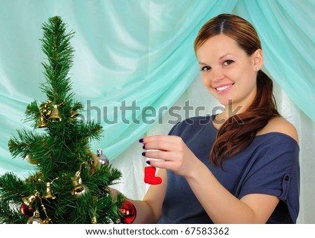 Young pregnant girl dresses up Christmas tree