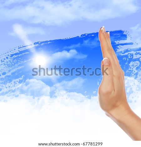 Hand wipes misted window at a blue sky