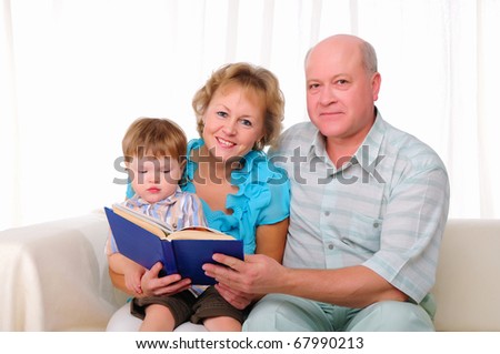 Grandmother, grandfather and grandson reading a book together. Symbol of the family.