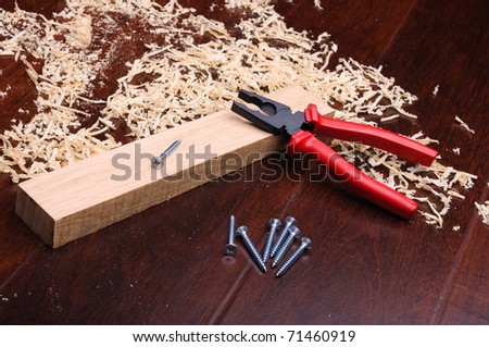 Shavings of wood, brick red and pliers on a dark background