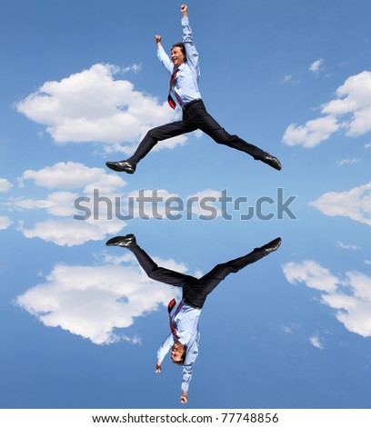 young businessman in a blue suit jumping in the air against blue sky