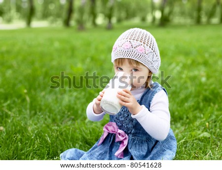 Portrait of a happy little girl drinking milk in the park