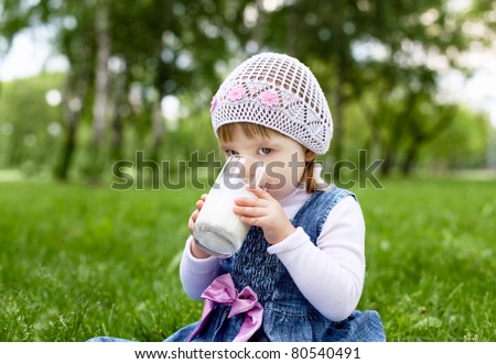 Portrait of a happy little girl drinking milk in the park