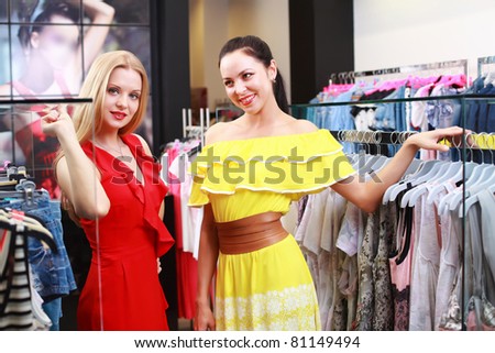 Two young beautiful girls choose their clothes in the store