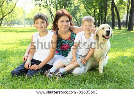 Mother and her two sons in the park with a golden retriever dog