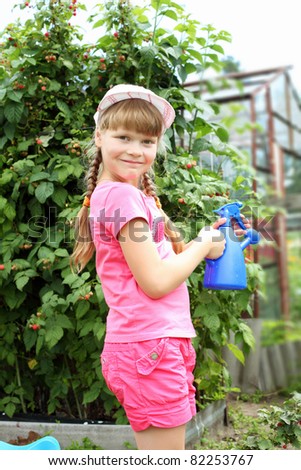 Girl watering plants in the summer garden