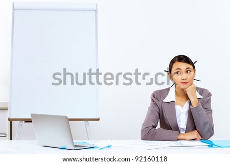 Young woman in business wear sitting with a phone in office