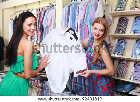 Girl seller helps shoppers choose the clothes in the store