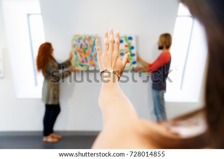 Young artists in gallery hanging painting on walls