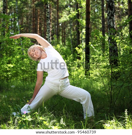 An elderly woman practices yoga in nature. The symbol of healthy lifestyle