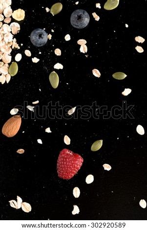 studio shoot of flakes, cereal, almond, dry fruit, seeds, fresh fruit on black background