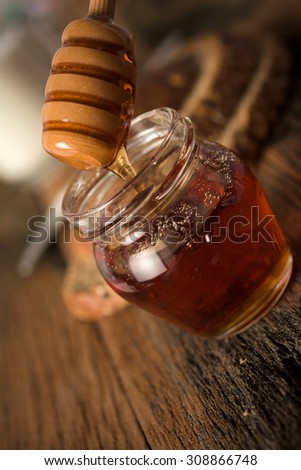 Studio shoot of Jar of honey and honey dipper, bread and knife, milk on wooden background