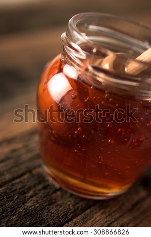 Studio shoot of Jar of honey and honey dipper on wooden background