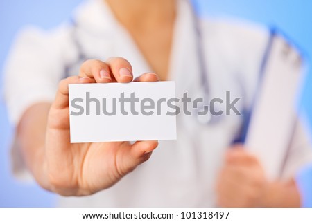 Doctor (woman) holding blank business card with copy space on blue