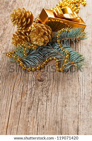 Christmas golden decorations on pine branch on wooden background