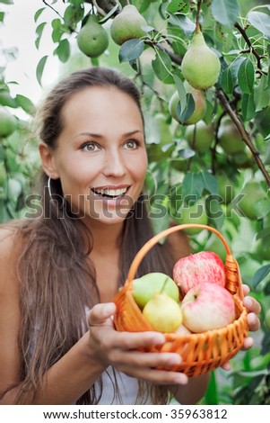 Beautiful woman in the garden with apples and pears in the crib