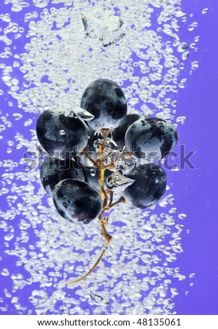 Bunch of grapes floating in blue water with air bubbles